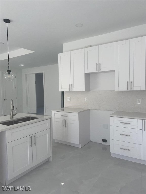 kitchen with decorative backsplash, pendant lighting, white cabinetry, and sink