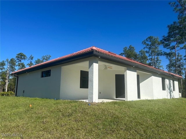 back of property with ceiling fan and a yard