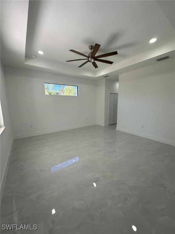 empty room featuring ceiling fan and a tray ceiling