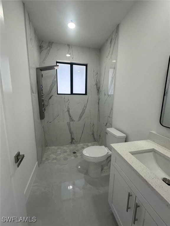 bathroom featuring tiled shower, vanity, and toilet