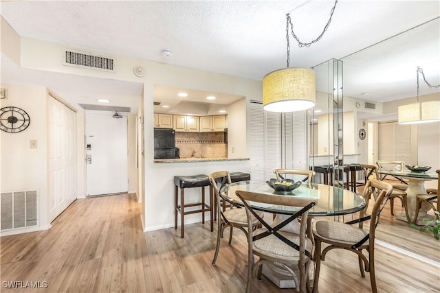 dining room featuring light hardwood / wood-style floors and a textured ceiling