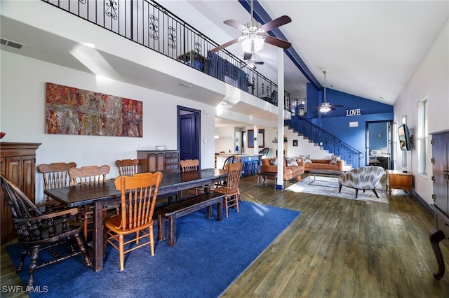 dining room with visible vents, a ceiling fan, wood finished floors, stairs, and high vaulted ceiling