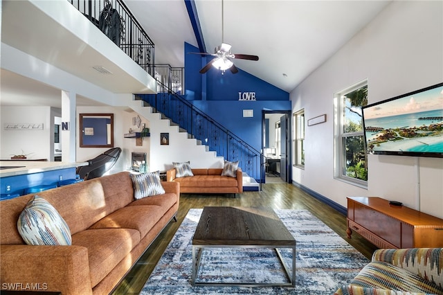 living room featuring ceiling fan, wood finished floors, high vaulted ceiling, baseboards, and stairs