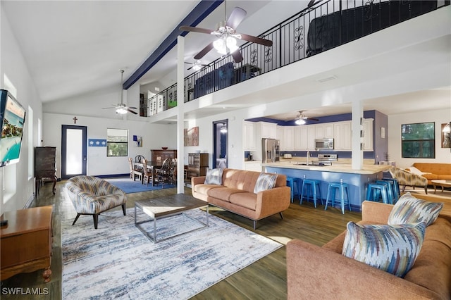 living room featuring hardwood / wood-style floors, high vaulted ceiling, sink, ceiling fan, and beamed ceiling