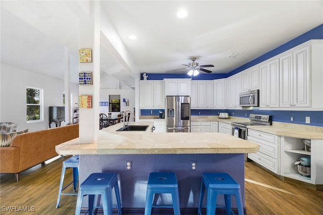 kitchen with white cabinets, a breakfast bar, stainless steel appliances, and sink