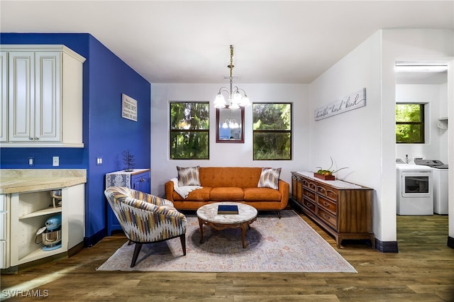 living room featuring washing machine and dryer, dark hardwood / wood-style floors, and an inviting chandelier