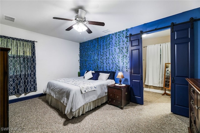 carpeted bedroom featuring visible vents, baseboards, and a barn door