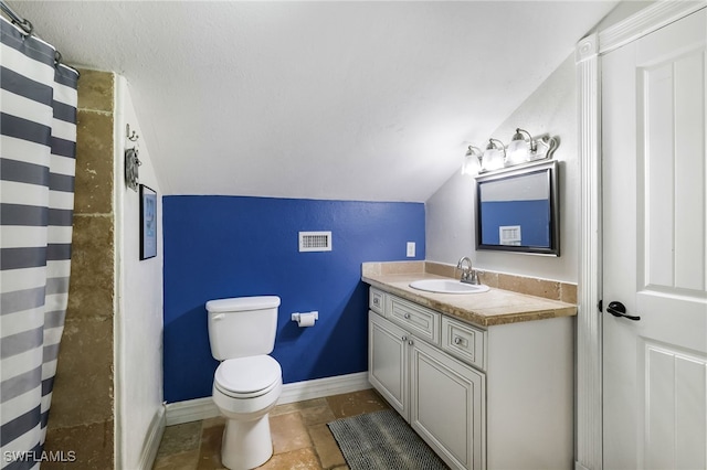 bathroom featuring baseboards, lofted ceiling, toilet, stone finish flooring, and vanity