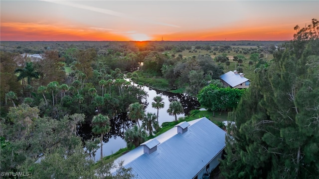 aerial view at dusk featuring a water view