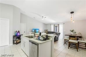 kitchen with stainless steel dishwasher, a kitchen island with sink, sink, pendant lighting, and white cabinets