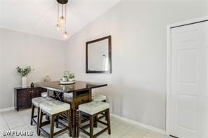 dining room with light tile patterned floors and vaulted ceiling