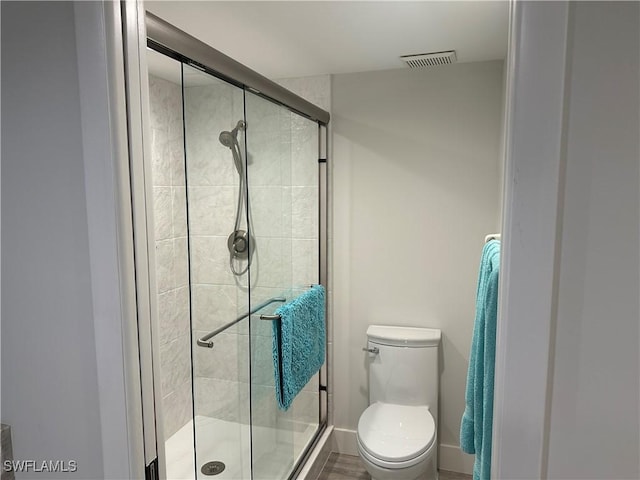 bathroom featuring toilet and a shower with shower door