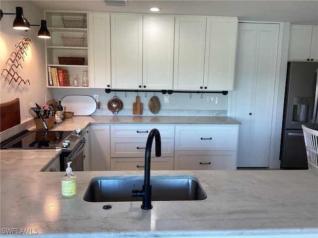 kitchen featuring light stone countertops, sink, white cabinets, and stainless steel appliances