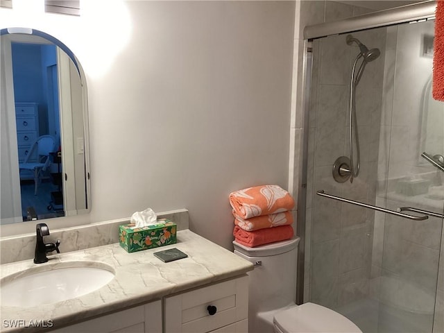 bathroom featuring vanity, toilet, and a shower with door