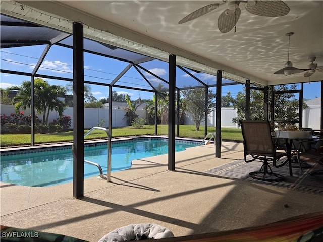 view of swimming pool with ceiling fan, a yard, a patio, and glass enclosure