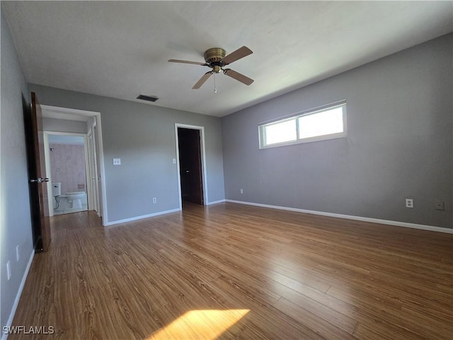 unfurnished bedroom featuring a spacious closet, wood-type flooring, and ceiling fan