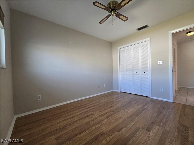 unfurnished bedroom with ceiling fan, dark hardwood / wood-style floors, and a closet