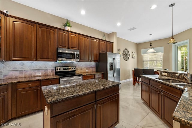 kitchen with appliances with stainless steel finishes, pendant lighting, sink, backsplash, and dark stone counters