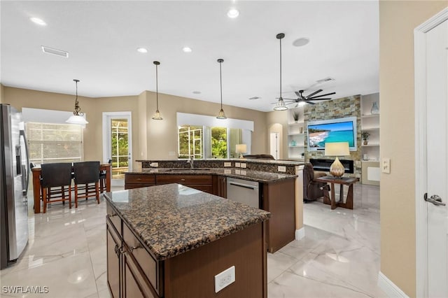 kitchen featuring a center island, decorative light fixtures, dark stone counters, and appliances with stainless steel finishes