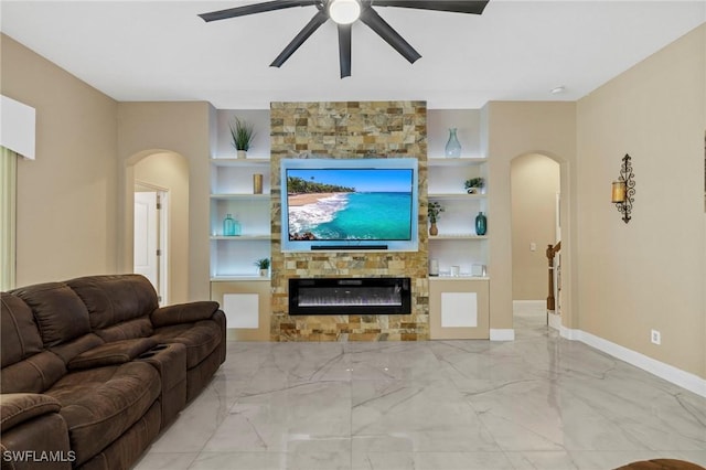 living room with ceiling fan, a stone fireplace, and built in features