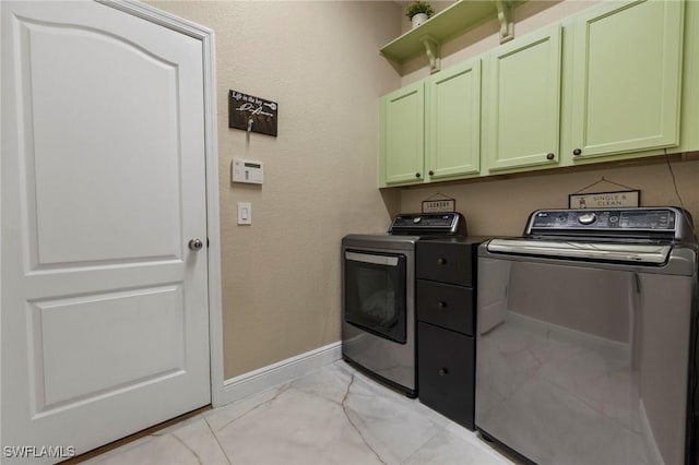 clothes washing area with cabinets and washing machine and clothes dryer