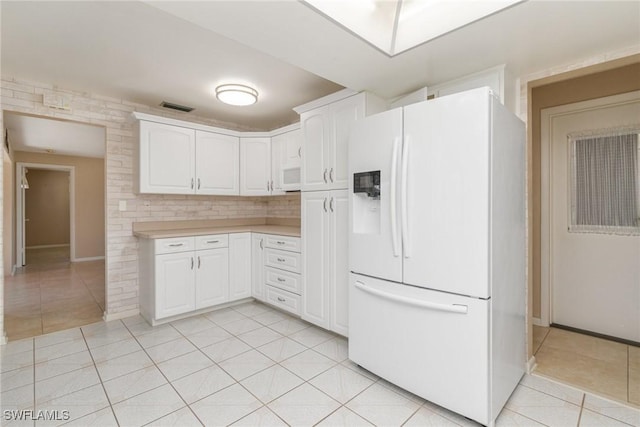 kitchen with decorative backsplash, white cabinets, light tile patterned flooring, and white appliances