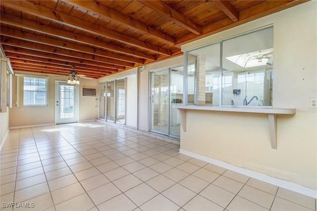 tiled empty room featuring ceiling fan, beam ceiling, and wooden ceiling