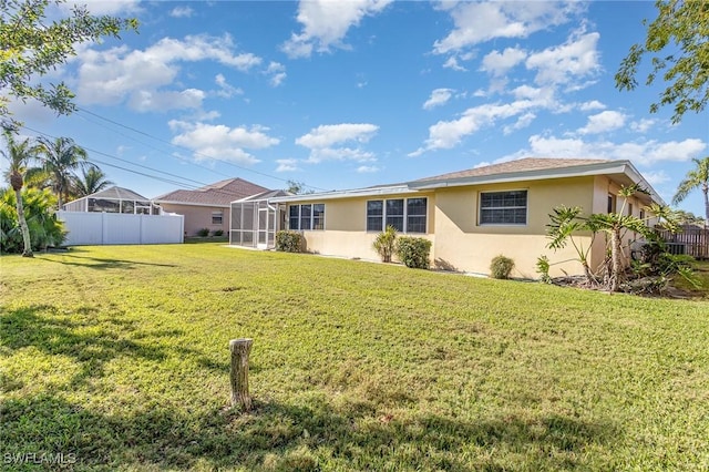 rear view of house with a lanai and a lawn