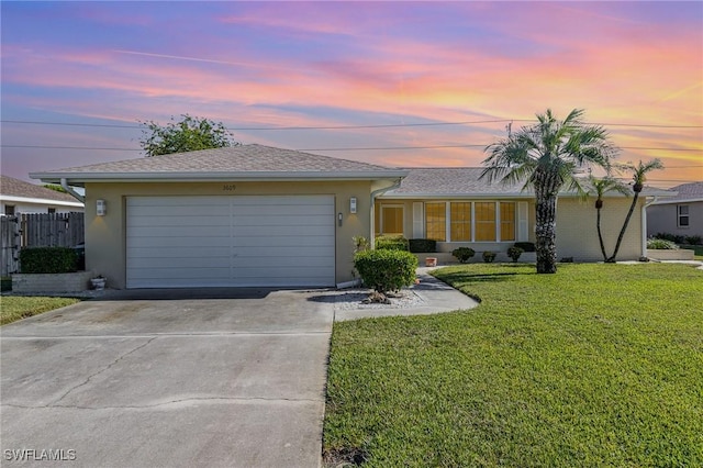 single story home featuring a garage and a lawn