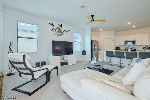 living room with ceiling fan, light tile patterned flooring, and sink