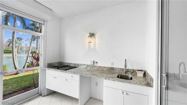 kitchen featuring plenty of natural light, a water view, white cabinetry, and sink