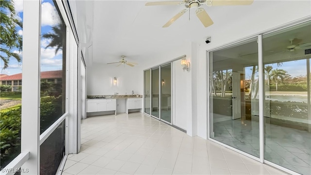 unfurnished sunroom featuring ceiling fan and sink