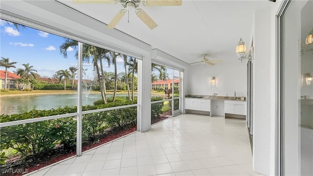 unfurnished sunroom featuring built in desk, a water view, a healthy amount of sunlight, and sink