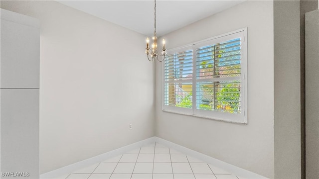 spare room with a chandelier and light tile patterned floors