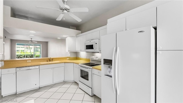 kitchen with white cabinets, white appliances, sink, and light tile patterned floors