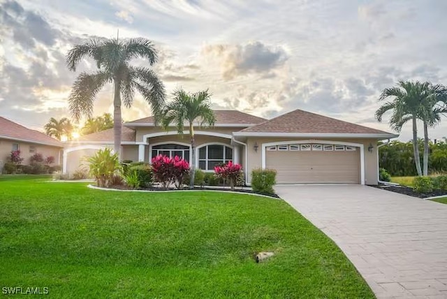 single story home featuring a garage and a lawn