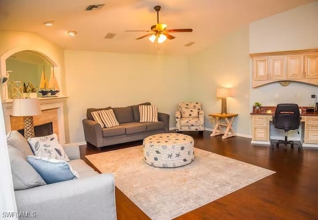 living room featuring ceiling fan, built in desk, dark wood-type flooring, and lofted ceiling