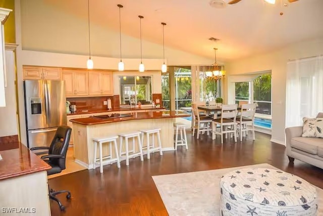 kitchen with dark hardwood / wood-style floors, stainless steel fridge, pendant lighting, lofted ceiling, and a kitchen island