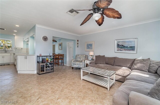 living room featuring ceiling fan, crown molding, light tile patterned floors, and sink