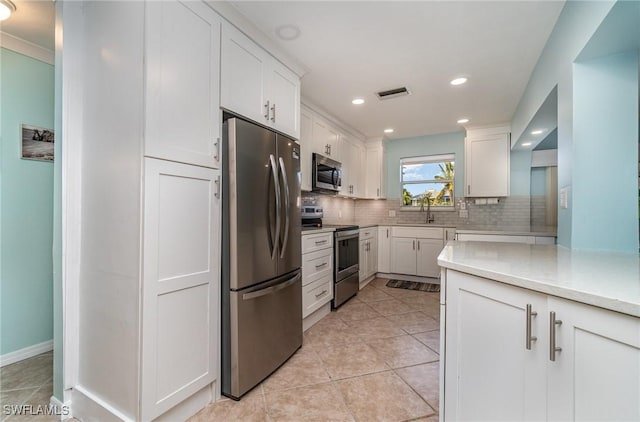 kitchen featuring stainless steel appliances, white cabinetry, and tasteful backsplash