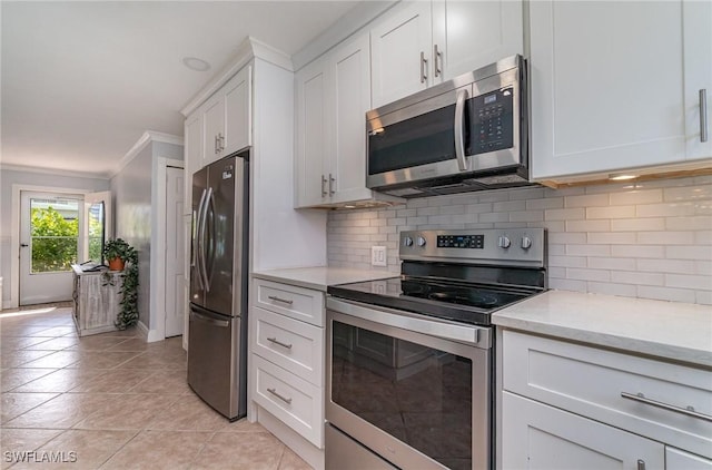 kitchen featuring appliances with stainless steel finishes, tasteful backsplash, light stone counters, light tile patterned floors, and white cabinets