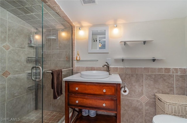 bathroom featuring walk in shower, vanity, and tile walls