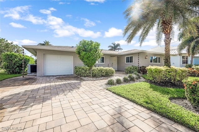 ranch-style home with a garage, decorative driveway, and stucco siding