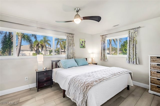 bedroom with multiple windows, ceiling fan, and light wood-type flooring