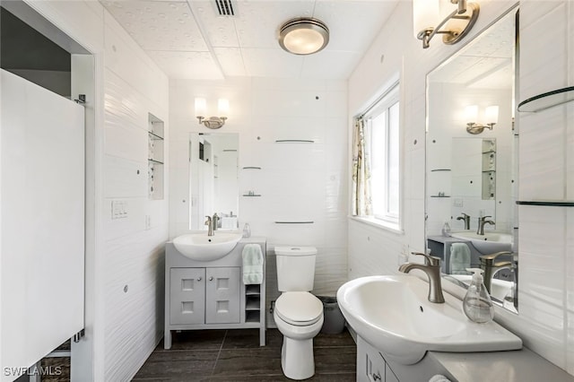 bathroom with vanity, toilet, and tile walls