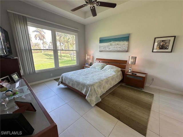 bedroom featuring ceiling fan, a raised ceiling, and light tile patterned floors