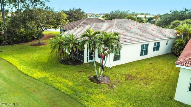 view of home's exterior with a sunroom and a lawn