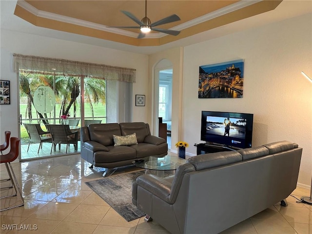 living room featuring a raised ceiling, ceiling fan, light tile patterned flooring, and ornamental molding