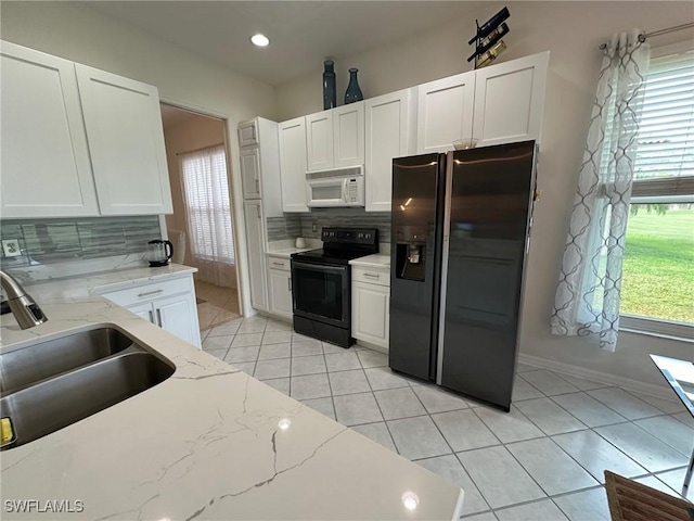 kitchen featuring tasteful backsplash, white cabinetry, black appliances, and light stone counters