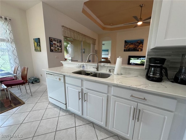 kitchen featuring a raised ceiling, white cabinetry, sink, and white dishwasher